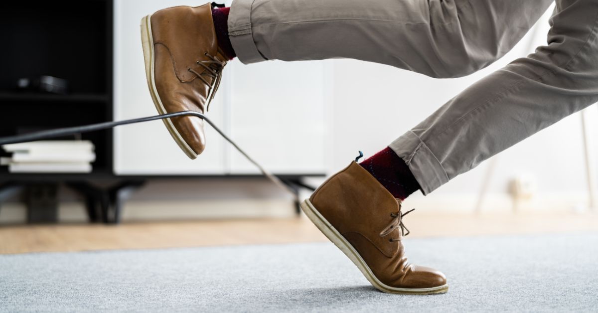 Person demonstrating fall risks: Tripping over a cord, highlighting the importance of falls prevention.